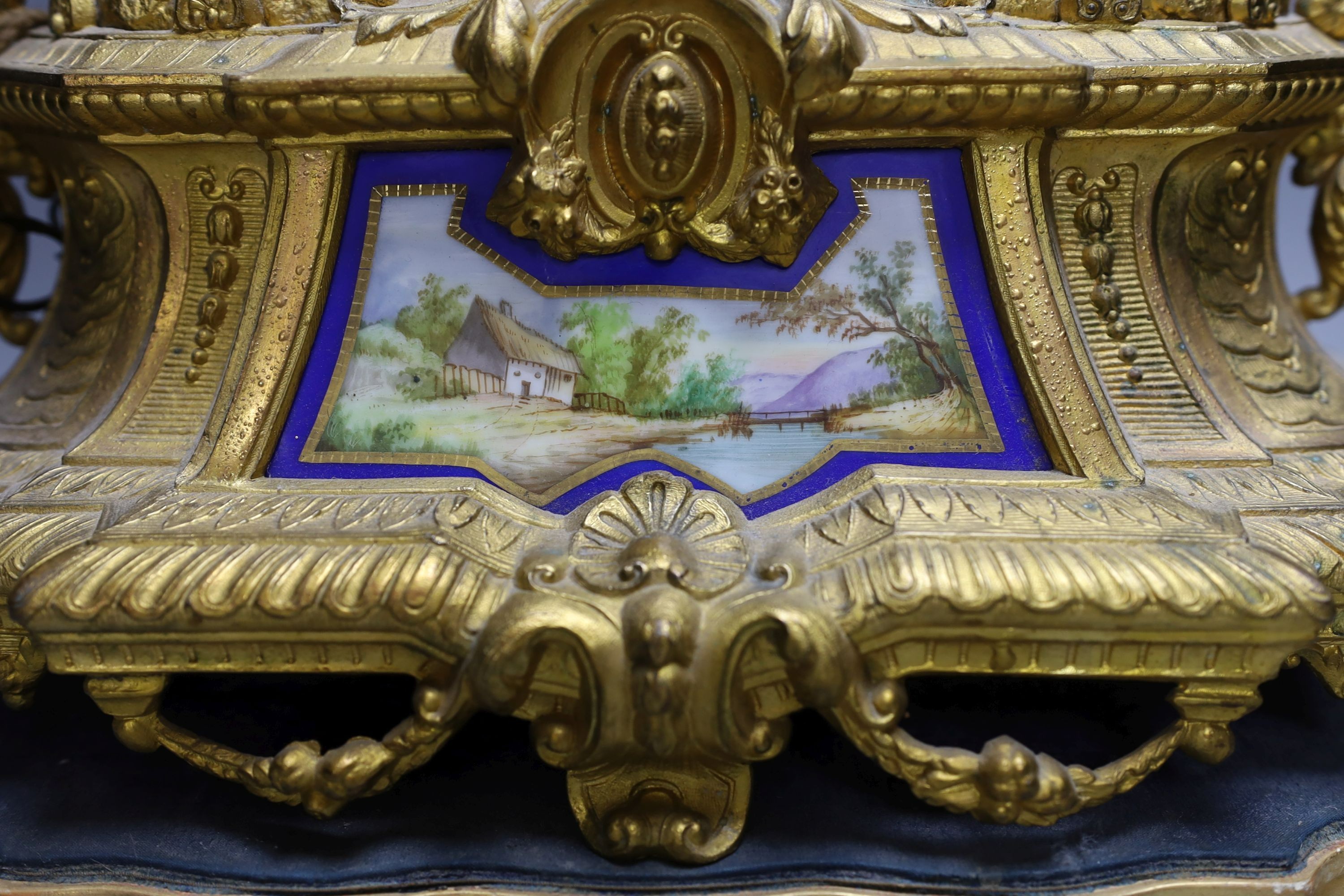 A 19th century gilt spelter mantel clock, having horse and jockey surmount with porcelain panels and circular porcelain dial, on shaped plinth base. 47cm